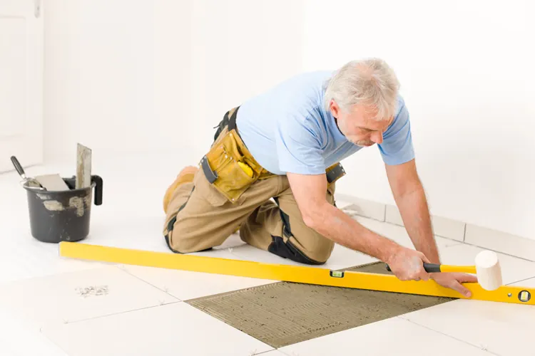A builder setting tile with a spirit level
